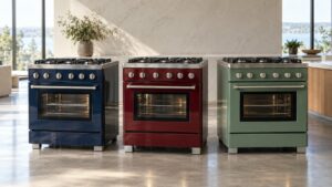 Three freestanding luxury ranges in different enamel colors lined up in a bright showroom